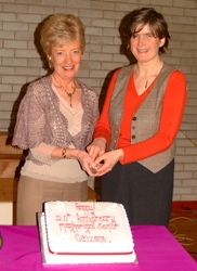 Rector’s wives, Maureen Cheevers and Bronwen Dark cut a cake to commemorate the 20th anniversary of Magheragall Parish Senior Citizens’ Club.
